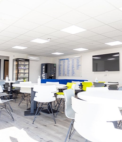 Family and waiting area inside the Huddersfield Town building, with tables, seating and a wall-mounted screen