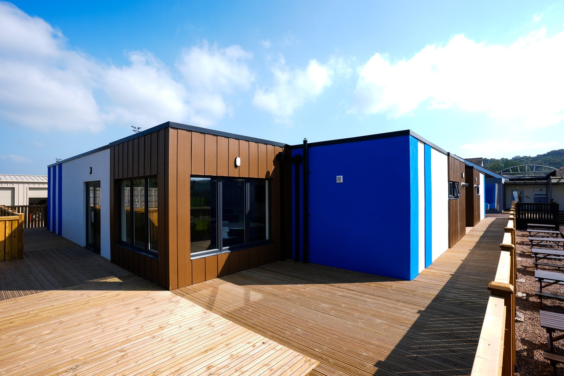 Completed modular changing-room building for Huddersfield Town AFC with timber-effect cladding, blue and white club-colour panels and timber decking